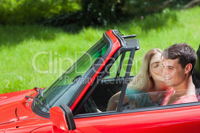 Pretty blonde kissing her boyfriend in red cabriolet