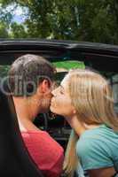 Attractive blonde kissing her boyfriend while having a ride in c