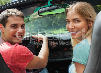 Cheerful couple looking at camera over shoulder