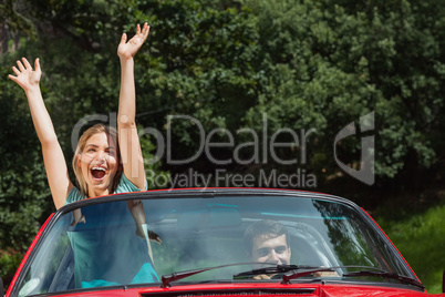 Happy couple having fun in their red cabriolet