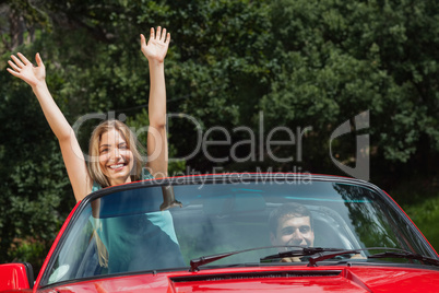 Happy woman having fun in cabriolet while her boyfriend driving
