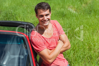 Smiling handsome man leaning against his cabriolet