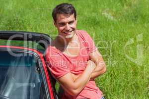 Smiling handsome man leaning against his cabriolet