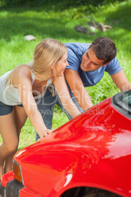 Happy couple pushing their broken down car