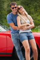 Loving couple hugging and leaning against cabriolet