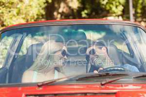 Loving couple in their red cabriolet having a ride