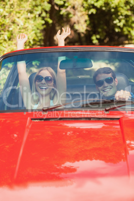 Loving couple having fun in their red cabriolet