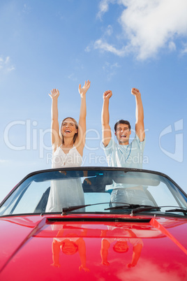 Cheerful couple standing in red cabriolet