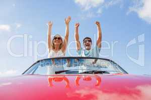 Crazy couple standing in red cabriolet
