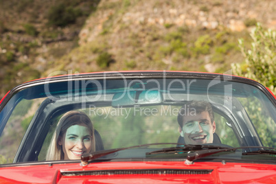 Front view of smiling couple in red cabriolet