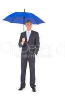 Businessman smiling at camera and holding blue umbrella