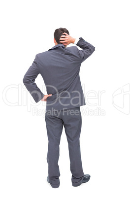 Young businessman standing back to camera scratching his head