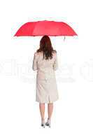 Businesswoman standing back to camera holding red umbrella