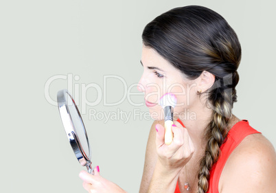 Attractive young woman looking at the mirror, applying make up