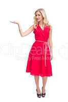 Cheerful woman in red dress presenting something in her hand