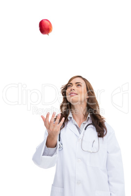 Smiling pretty doctor throwing apple