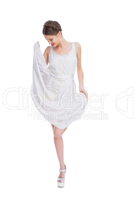 Smiling woman playing with her white summer dress