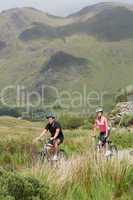 Athletic couple biking through wilderness