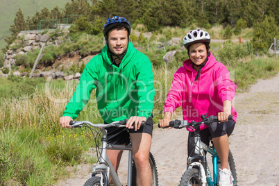 Happy couple on a bike ride wearing hooded jumpers