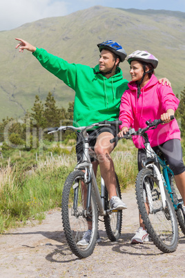 Athletic couple on a bike ride wearing hooded jumpers with man p
