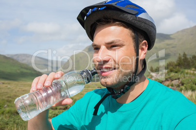 Fit man wearing helmet drinking water