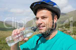 Fit man wearing helmet drinking water