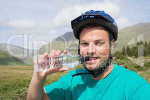 Fit man wearing bike helmet drinking water