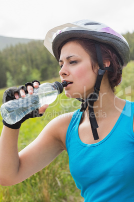 Fit woman wearing bike helmet drinking water