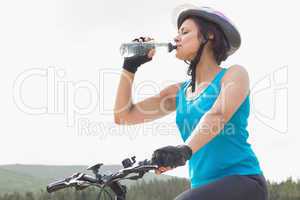 Athletic woman on mountain bike drinking water