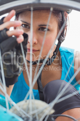 Focused woman adjusting her spokes on bike wheel