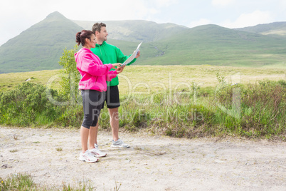 Athletic couple holding a map and looking ahead