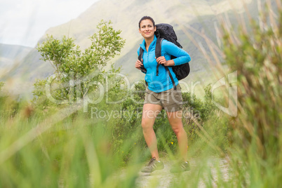 Female hiker with backpack walking and smiling