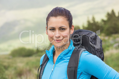 Attractive female hiker with backpack smiling at camera