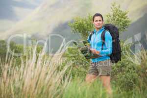 Attractive female hiker with backpack holding a map