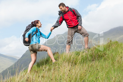 Attractive hiker helping his girlfriend uphill