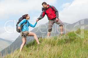 Attractive hiker helping his girlfriend uphill