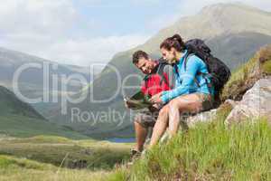 Couple taking a break after hiking uphill and reading map