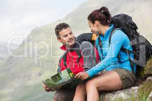 Couple resting after hiking uphill and holding map