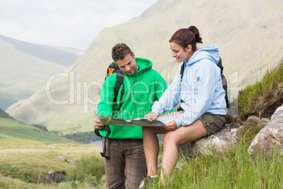 Couple resting after hiking uphill and looking at map