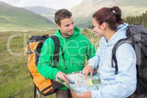 Happy couple resting after hiking uphill and consulting map