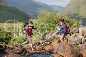 Couple crossing a river on a hike