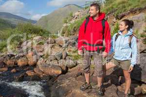 Couple standing at edge of river on a hike