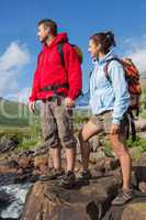 Couple standing at edge of river on a hike holding hands