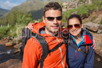Couple wearing rain jackets and sunglasses smiling at camera