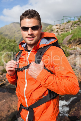 Man wearing rain jacket and sunglasses smiling at camera