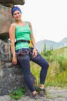 Attractive female rock climber leaning on rock face smiling at c