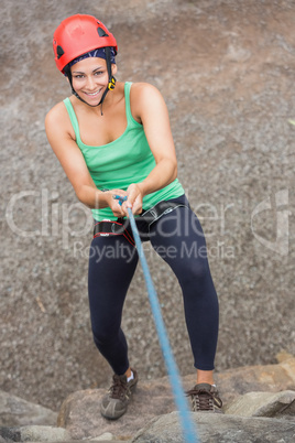 Smiling girl abseiling down rock face