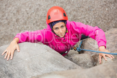 Smiling girl climbing up rock face