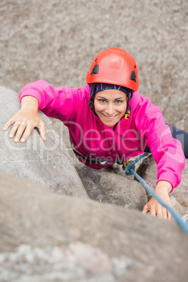 Happy girl climbing up rock face