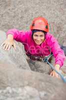 Happy girl climbing up rock face